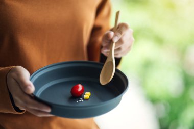 Diyet konsepti için az miktarda yiyecek tutan ve yiyen bir kadının yakın plan görüntüsü