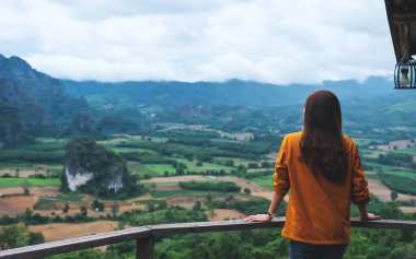 Güzel, sisli bir dağa ve doğa manzarasına bakan bir kadın gezginin dikiz görüntüsü.