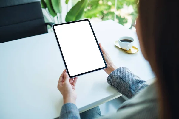 Mockup image of a woman holding digital tablet with blank white desktop screen in the office