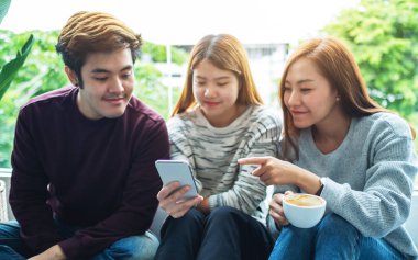 Birlikte takılırken aynı cep telefonuna bakan bir grup genç.