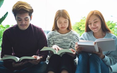 Bir grup genç birlikte oturup kitap okumaktan zevk alıyorlar.