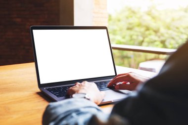 Laptop bilgisayar klavyesinde yazı yazan ve kullanan bir kadının resmi. Tahta masadaki boş beyaz masaüstü ekran.