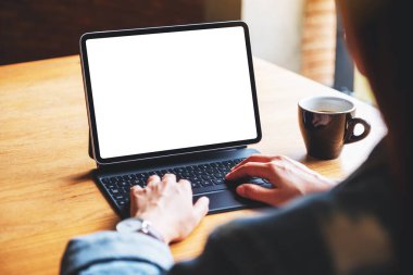 Bilgisayar bilgisayarı olarak boş beyaz masaüstü ekranı olan dijital tablet klavyesinde yazı yazan ve kullanan bir kadının görüntüsü 