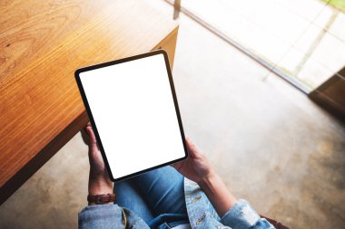 Boş beyaz masaüstü ekran ile dijital tablet tutan bir kadının en üst görünüm görüntüsü 