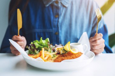 Restoranda balık ve cips yiyen bir kadının yakın plan görüntüsü.