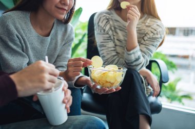 Arkadaşların birlikte patates cipsi yiyip içerken çekilmiş yakın plan görüntüleri. 