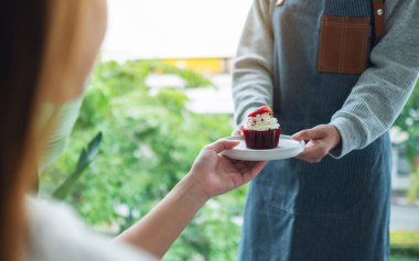Bir garson müşteriye kırmızı kadife kek ikram ediyor.