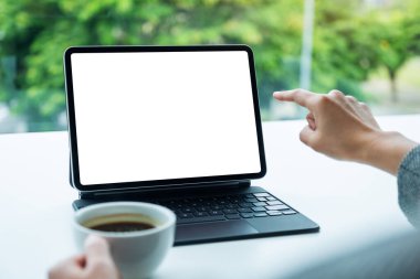 Ofiste bilgisayar bilgisayarı olarak boş masaüstü beyaz ekranı olan dijital tableti kullanan ve işaret eden bir kadının görüntüsü