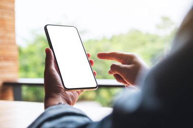 Boş beyaz masaüstü ekranlı cep telefonunu tutan ve işaret eden bir kadının görüntüsü