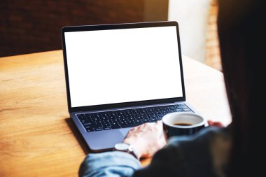 Laptop bilgisayar klavyesinde yazı yazan ve kullanan bir kadının resmi. Tahta masadaki boş beyaz masaüstü ekran.