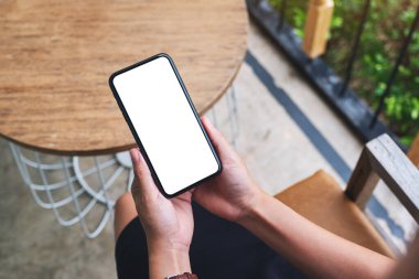 Boş beyaz masaüstü ekran ile cep telefonu tutan bir kadının en üst görünüm görüntüsü