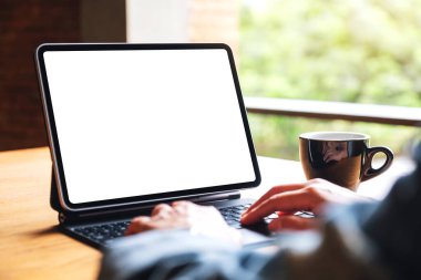 Bilgisayar bilgisayarı olarak boş beyaz masaüstü ekranı olan dijital tablet klavyesinde yazı yazan ve kullanan bir kadının görüntüsü