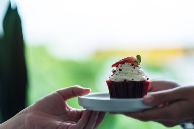 Bir garson müşteriye kırmızı kadife kek ikram ediyor.