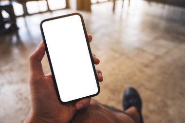 Kafede elinde siyah cep telefonu olan beyaz ekranlı bir adamın görüntüsü.