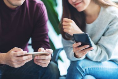 Gençler birlikte otururken cep telefonlarıyla oyun oynuyorlar.