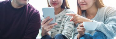 Birlikte takılırken aynı cep telefonuna bakan bir grup genç.