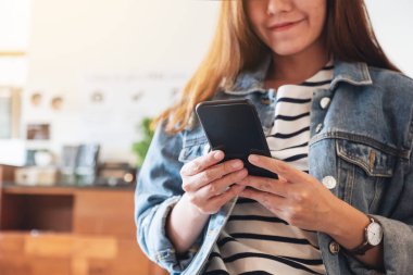 Asyalı güzel bir kadının akıllı telefonu tutarken ve kullanırken yakın plan görüntüsü.