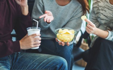 Arkadaşların birlikte patates cipsi yiyip içerken çekilmiş yakın plan görüntüleri.