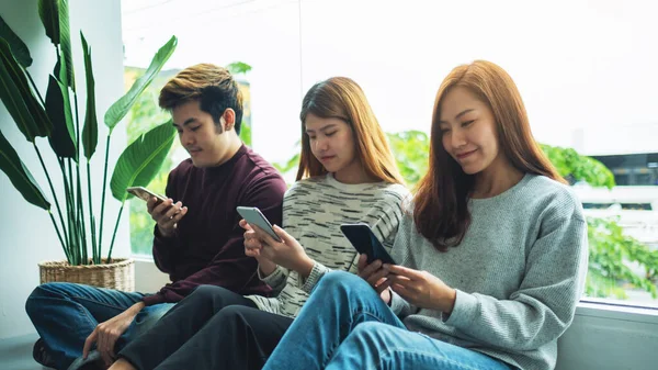 Bir grup genç yan yana otururken cep telefonu kullanıyor ve bakıyor