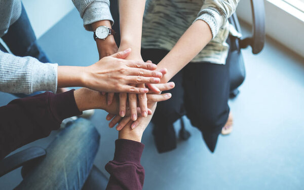 Closeup image of business team standing and joining their hands together in office