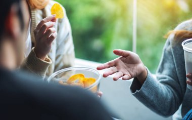 Arkadaşların birlikte patates cipsi yiyip içerken çekilmiş yakın plan görüntüleri.