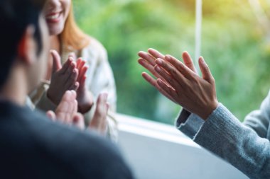 Bir grup genç birlikte otururken el çırpıyor.