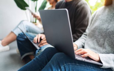 Bir grup genç birlikte oturup dizüstü bilgisayar ve dijital tablet kullanıyorlar.