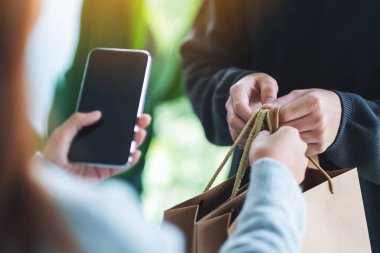 Cep telefonu tutan ve alışveriş torbaları alan bir kadın teslimatçı.