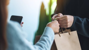 Cep telefonu tutan ve alışveriş torbaları alan bir kadın teslimatçı.