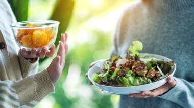 Kadınlar patates cipsi yemeyi ve sebze salatasını reddetmek için el işareti yapmayı seçiyorlar.