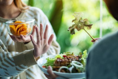 Kadınlar patates cipsi yemeyi ve sebze salatasını reddetmek için el işareti yapmayı seçiyorlar.