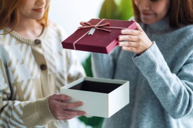 İki genç Asyalı kadın birlikte bir hediye kutusu açıyor.