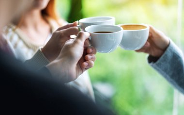 Bir grup genç, içki içip kahve fincanlarını tokuşturmaktan zevk alıyordu.