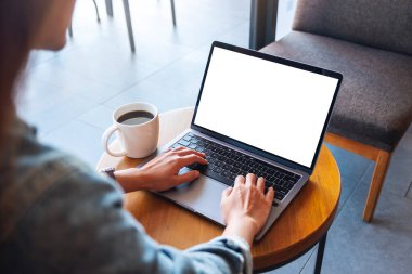 Kafedeki boş beyaz masaüstü ekran ile dizüstü bilgisayar klavyesinde yazan ve kullanan bir kadının görüntüsü