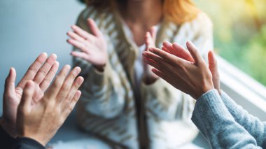 Bir grup genç birlikte otururken el çırpıyor.