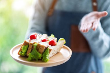 Yakından bakınca, servis yapan bir garsonun ahşap tabakta tüm buğday sandviçini gösterdiğini görüyoruz.