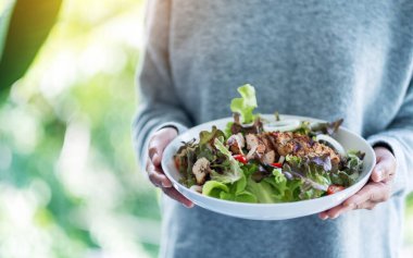 Yakından bakınca elinde bir tabak tavuk salatası tutan bir kadın görülüyor. 