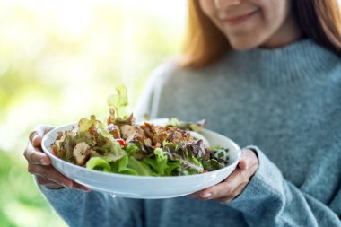 Elinde bir tabak tavuk salatası tutan genç bir kadının yakın plan fotoğrafı. 