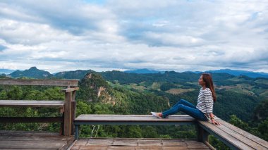 Oturan ve güzel bir dağ manzarasına bakan bir kadın gezginin portresi. 
