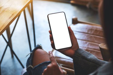 Boş beyaz masaüstü ekranlı cep telefonunu tutan ve işaret eden bir kadının görüntüsü