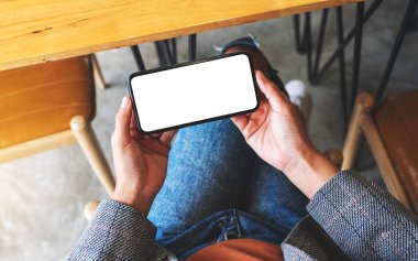 Boş beyaz masaüstü ekran ile cep telefonu tutan bir kadının en üst görünüm görüntüsü