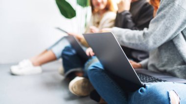 Bir grup genç birlikte oturup dizüstü bilgisayar ve dijital tablet kullanıyorlar.