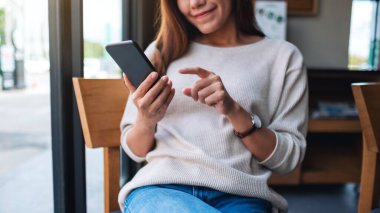 Asyalı güzel bir kadının akıllı telefonu tutarken ve kullanırken yakın plan görüntüsü.