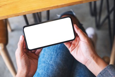Boş beyaz masaüstü ekran ile cep telefonu tutan bir kadının en üst görünüm görüntüsü