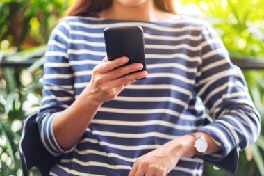 Asyalı güzel bir kadının akıllı telefonu tutarken ve kullanırken yakın plan görüntüsü.