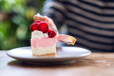 Tabakta çilekli kek yiyen bir kadının yakın plan görüntüsü.