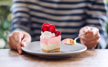 Tabakta çilekli kek yiyen bir kadının yakın plan görüntüsü.