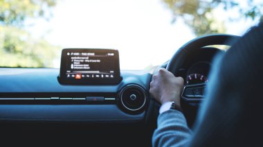 Bir kadının direksiyon tutarken yolda araba kullanırken ki görüntüsü.