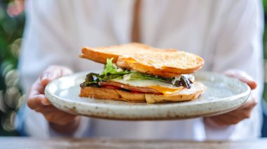 Yakından bakınca, elinde jambonlu sandviçle servis yapan bir kadın görülüyor.