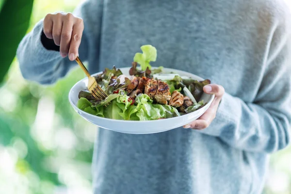 Elinde tavuk salatası tutan ve yiyen bir kadının yakın plan görüntüsü.
